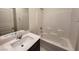 Clean bathroom with white tile, single vanity, and bathtub at 7672 Lush Oasis Ave, Las Vegas, NV 89113