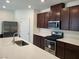 Modern kitchen with dark brown cabinets, stainless steel appliances, and white countertops at 7672 Lush Oasis Ave, Las Vegas, NV 89113