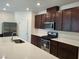 Modern kitchen with dark brown cabinets, stainless steel appliances, and white countertops at 7672 Lush Oasis Ave, Las Vegas, NV 89113