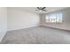 Spacious bedroom featuring gray carpet, ceiling fan, and a large window for ample natural light at 7900 Holly Knoll Ave, Las Vegas, NV 89129