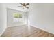 A cozy bedroom showcases neutral paint, a window, wood floors and a ceiling fan at 7900 Holly Knoll Ave, Las Vegas, NV 89129