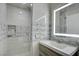 Modern bathroom featuring sleek vanity with illuminated mirror, and a tiled shower with niche at 1140 Woodcastle St, Henderson, NV 89052