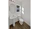 Clean bathroom with pedestal sink, toilet, and wood-look tile floor at 3615 American Pie Ct, Las Vegas, NV 89129
