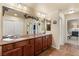 Bathroom featuring a dual sink vanity, decorative mirrors, and wood look tile flooring at 6595 Creekside Cellars Ct, Las Vegas, NV 89139