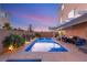Inviting pool and backyard with covered patio and lush landscaping under a dusk sky at 6595 Creekside Cellars Ct, Las Vegas, NV 89139