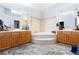Luxurious bathroom with dual vanities, a large soaking tub, and neutral tiled flooring at 9109 Lazy Hill Cir, Las Vegas, NV 89117