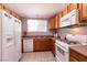 Galley kitchen with wood cabinets, white appliances, and tiled floors at 2535 River Oaks Dr, Las Vegas, NV 89156