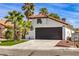 Front view of a house with a dark garage door and palm trees at 2674 Alwoodley Cir, Las Vegas, NV 89142