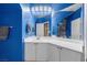 Bright blue bathroom with white vanity, cabinets, and an oversized framed mirror at 41 Voltaire Ave, Henderson, NV 89002