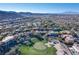 Aerial view of the community showcasing lush golf course, homes, and mountain views at 1549 Foothills Village Dr, Henderson, NV 89012