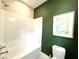 Clean bathroom with white subway tile, a bathtub, and a green accent wall at 210 Abbey Hill St, Henderson, NV 89012