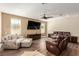 Comfortable living room features a ceiling fan, large windows, plush seating, and wood floors at 6524 Summershade St, North Las Vegas, NV 89086
