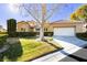 Tan two-story house with a white garage door and landscaped lawn at 7943 Harbour Towne Ave, Las Vegas, NV 89113