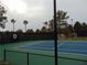 Fenced tennis court with green and blue surface and lush surrounding greenery at 7943 Harbour Towne Ave, Las Vegas, NV 89113