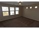 Large bedroom with brown carpet, multiple windows, and a ceiling light at 10264 Headrick Dr, Las Vegas, NV 89166