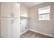 Bright laundry room featuring white cabinets and wood-look floors at 10823 Crestview Pointe Ave, Las Vegas, NV 89166