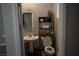 Small half-bath featuring a pedestal sink, toilet, decorative mirror, and rack at 2509 Piacenza Pl, Henderson, NV 89044