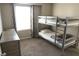 Bedroom with a gray bunk bed, gray dresser, and a window with patterned curtains at 2509 Piacenza Pl, Henderson, NV 89044