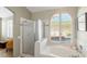 Bathroom with a shower stall, garden tub, and arched window with plantation shutters at 279 Windsong Echo Dr, Henderson, NV 89012