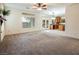 Spacious carpeted living room featuring bright window, ceiling fan, and doors to kitchen at 575 Dusty Palms Ln, Henderson, NV 89052