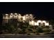 Stone house exterior at night with landscape lighting and lush landscaping at 768 Tozzetti Ln, Henderson, NV 89012