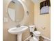 Small bathroom with pedestal sink, toilet and large round mirror at 8477 Orly Ave, Las Vegas, NV 89143