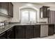 Modern kitchen with dark cabinetry, granite countertops, and a double sink at 8543 Alpine Vineyards Ct, Las Vegas, NV 89139