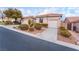 Tan house with tile roof, two-car garage, and landscaped yard at 10134 Donald Weese Ct, Las Vegas, NV 89129