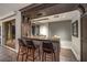 Stylish bar area with bar stools, a countertop, and a window with blinds, adjacent to the living room at 1705 Corta Bella Dr, Las Vegas, NV 89134