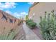 Beautiful side yard featuring lush greenery and a tiled walkway with a painted mural on the fence at 10125 James Harbin Ave, Las Vegas, NV 89129