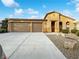 Tan three-car garage house with landscaped yard at 6162 Denton Ranch Rd, Las Vegas, NV 89131