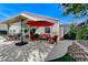Backyard patio area featuring outdoor furniture and landscaping with mature trees and a vibrant red umbrella at 1595 Cattle Ranch Pl, Henderson, NV 89002