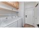 Well-lit laundry room featuring modern white washer and dryer with shelving and cabinets at 1595 Cattle Ranch Pl, Henderson, NV 89002