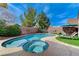 Backyard pool with jacuzzi, landscaping, and lounge chairs with grass and blue tile trim at 1595 Cattle Ranch Pl, Henderson, NV 89002