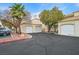 Exterior view of garages with white doors and driveway, parking area, and mature landscaping at 1900 N Torrey Pines Dr # 112, Las Vegas, NV 89108