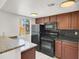 Cozy kitchen featuring black appliances, dark wood cabinets, granite countertops, and a window for natural lighting at 5493 Indian River Dr # 383, Las Vegas, NV 89103