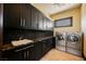 Laundry room with modern washer and dryer, granite countertop, and dark cabinetry at 646 Saint Croix St, Henderson, NV 89012