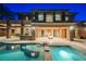 Stunning home exterior with a sparkling pool, fire pit, and covered patio with stone columns at 646 Saint Croix St, Henderson, NV 89012