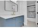 Modern bathroom features a sleek blue vanity, gold fixtures, and a marble-tiled shower behind a sliding glass door at 6586 W Mesa Vista Ave, Las Vegas, NV 89118