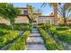 Elegant home entrance with a paved walkway, lush landscaping, exterior lighting, and a custom wrought iron door at 10117 Summit Canyon Dr, Las Vegas, NV 89144