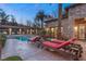 Backyard with covered patio, pool, and elegant stone house featuring lounge chairs at 10117 Summit Canyon Dr, Las Vegas, NV 89144