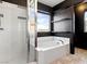 Elegant bathroom featuring a soaking tub with a shower, neutral tile, and stylish black accents at 1012 Water Cove St, Henderson, NV 89011