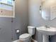 Modern half-bathroom featuring sleek fixtures, pedestal sink, and stylish round mirror at 1012 Water Cove St, Henderson, NV 89011