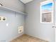 Bright laundry room with a window, shelving, tile flooring and painted light gray walls at 1012 Water Cove St, Henderson, NV 89011