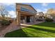 View of the backyard with a covered patio, green grass, and a brick-lined walkway at 11290 Hazel Rock St, Las Vegas, NV 89179