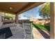 Covered patio with rocking chairs overlooks a well-maintained backyard with brick accents at 11290 Hazel Rock St, Las Vegas, NV 89179