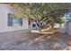 Backyard with gravel, mature trees and a partial view of the house at 12 Oro Valley Dr, Henderson, NV 89052