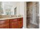 Bathroom with a double mirror, wooden cabinets, and a walk-in shower with marbled tile surround at 12 Oro Valley Dr, Henderson, NV 89052