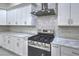 Close-up of a modern stove in a kitchen with white cabinets and elegant marble backsplash at 1202 S Rancho Dr, Las Vegas, NV 89102