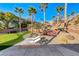 Backyard features a tiered patio area with an outdoor kitchen, waterfall feature, putting green, and desert landscaping at 2064 Poetry Ave, Henderson, NV 89052